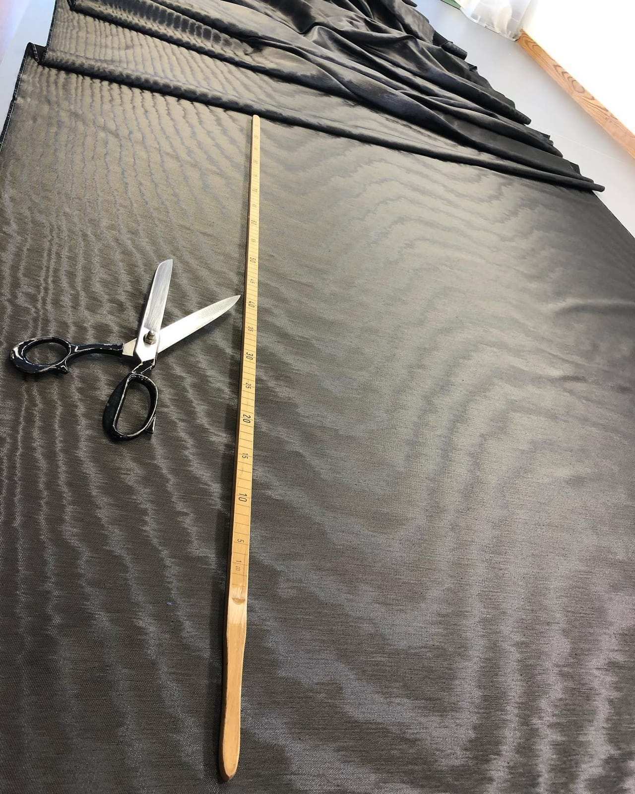 Dunkler Vorhangstoff mit Meterstab und Schere auf dem Zuschnitttisch