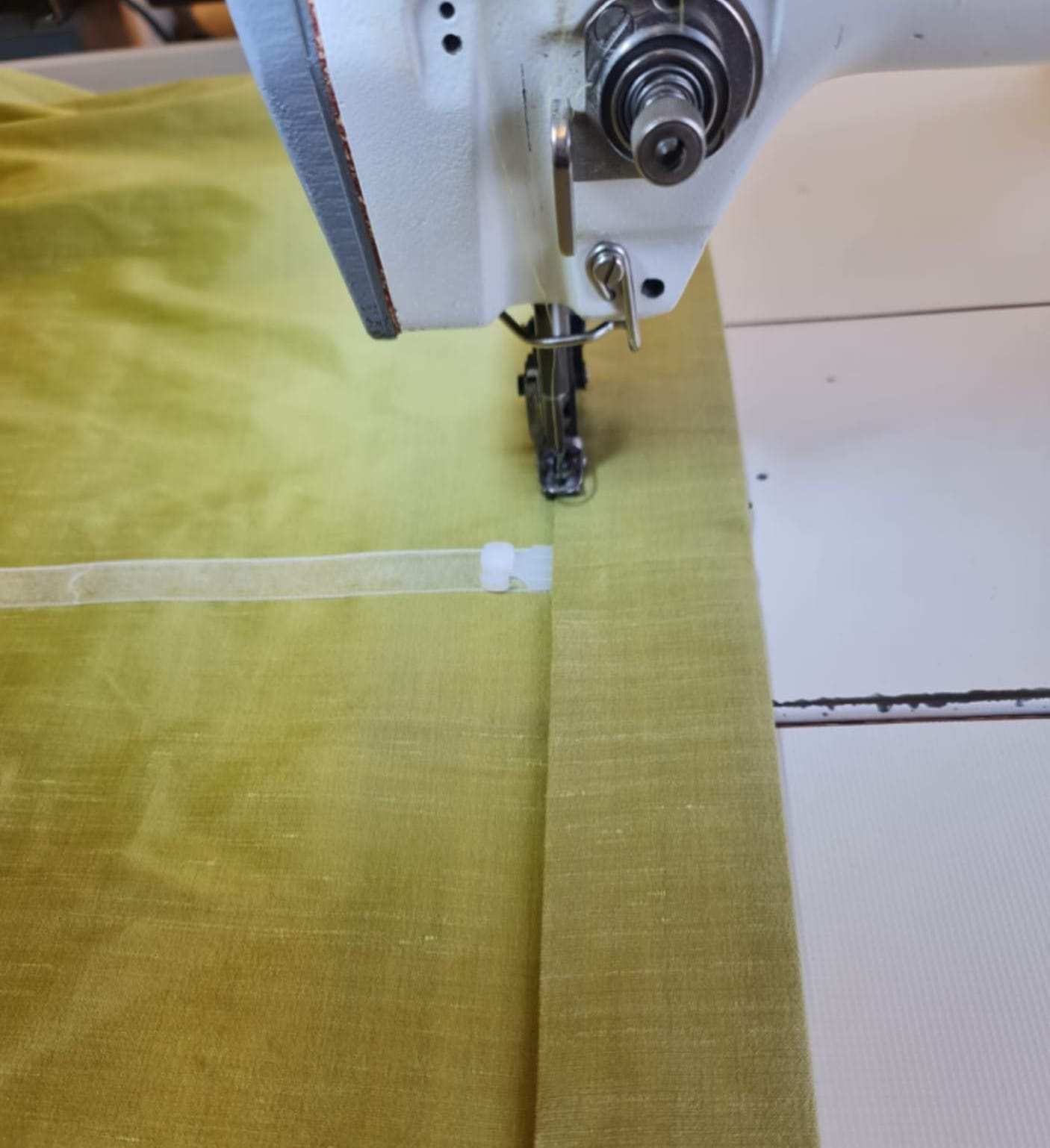 Olivgrüner Vorhangstoff unter der Nähmaschine