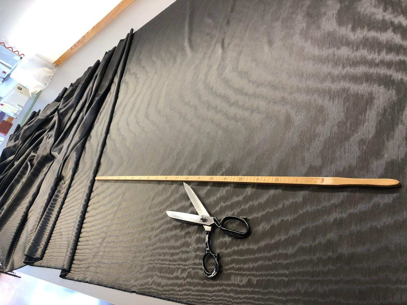 Dunkler Vorhangstoff auf dem Zuschnitttisch, mit Schere und Maßstab