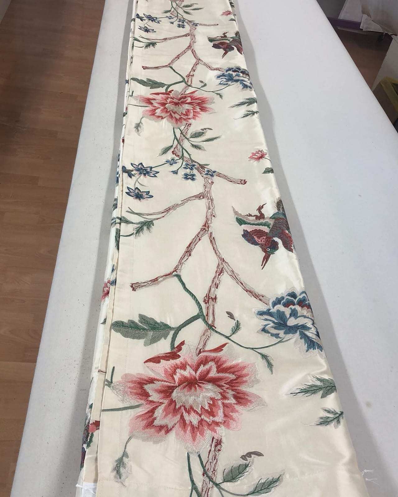Bestickte Seidenbahn auf dem Zuschnitttisch der Werkstatt